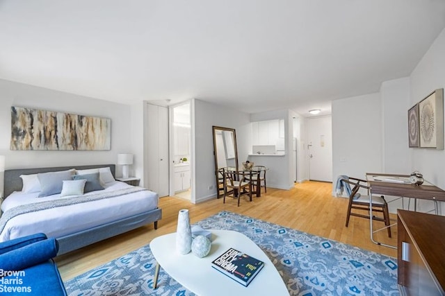 bedroom with ensuite bath and light wood-style flooring