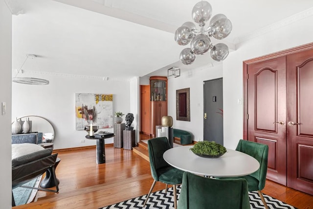 dining space featuring light wood finished floors, baseboards, a notable chandelier, and ornamental molding