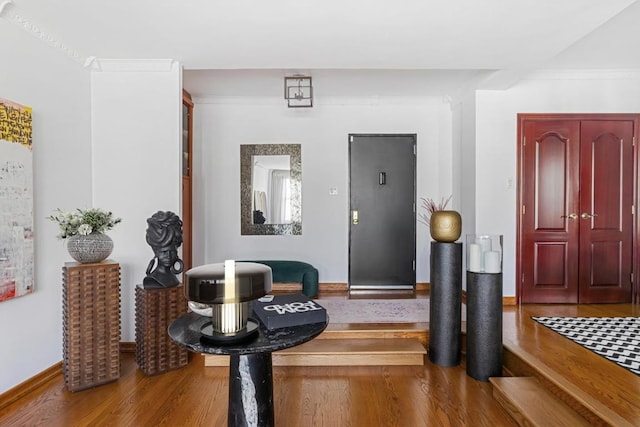 interior space featuring crown molding, baseboards, and wood finished floors