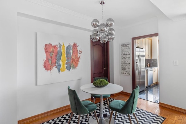 dining area featuring a chandelier, light wood-type flooring, baseboards, and crown molding