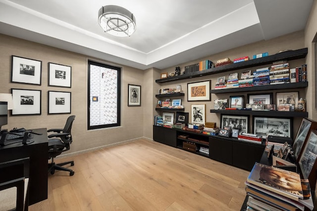 home office featuring light hardwood / wood-style floors and a tray ceiling