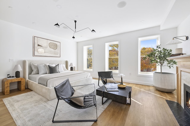 bedroom featuring multiple windows, wood finished floors, and a high end fireplace