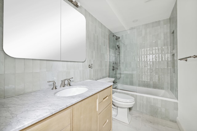 bathroom with toilet, vanity, tiled shower / bath, marble finish floor, and tasteful backsplash