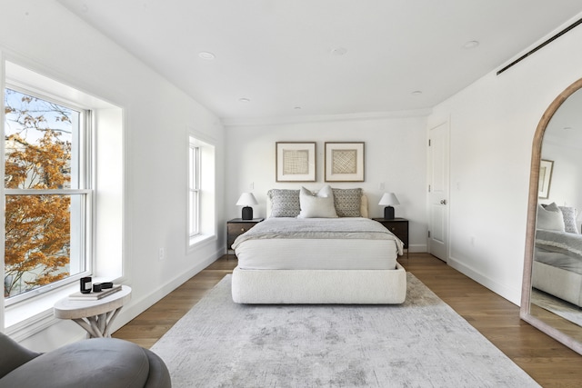 bedroom with arched walkways, baseboards, and wood finished floors