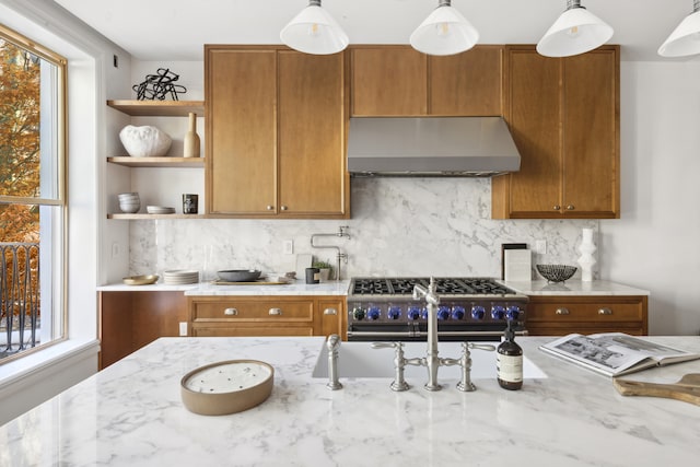 kitchen featuring high end stove, exhaust hood, brown cabinets, decorative backsplash, and open shelves