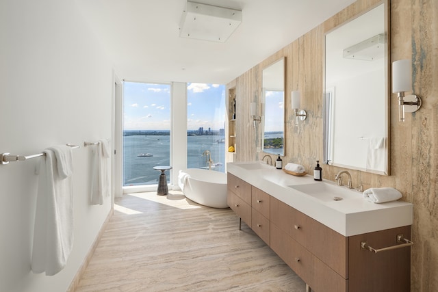 full bathroom with a sink, a soaking tub, a wall of windows, and double vanity