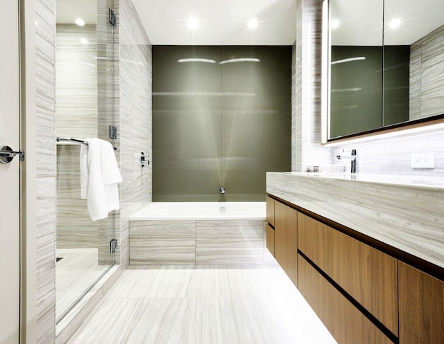 full bath with tile walls, a shower stall, a washtub, and vanity