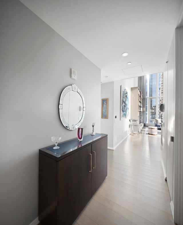 hallway featuring baseboards, recessed lighting, and wood finished floors