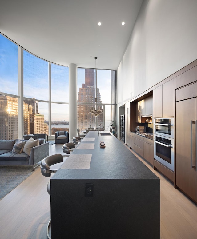 kitchen featuring expansive windows, paneled refrigerator, dark countertops, light wood-type flooring, and open floor plan