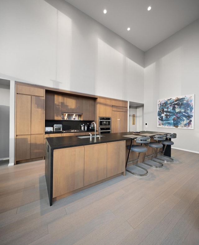 kitchen with a sink, a towering ceiling, modern cabinets, and dark countertops