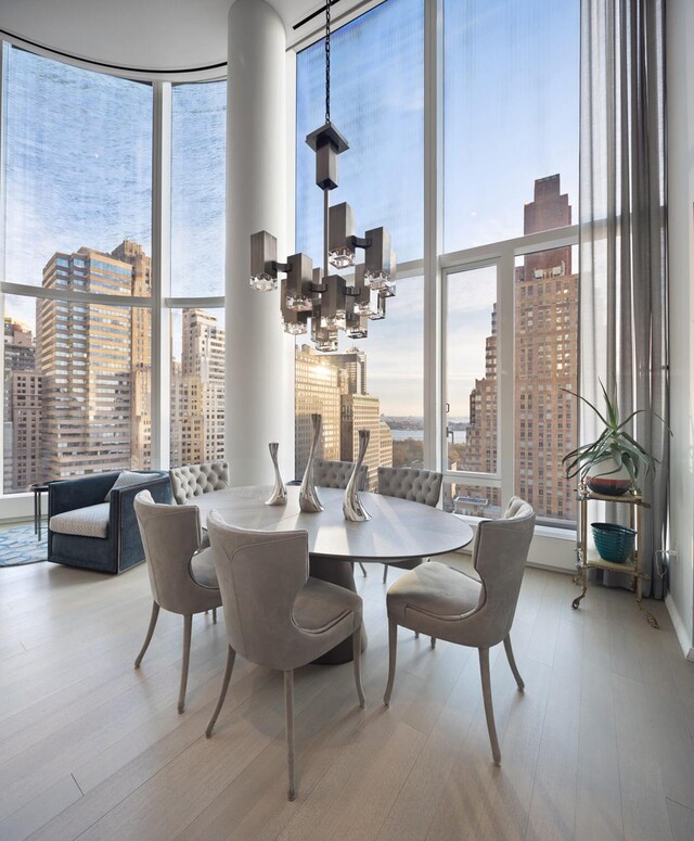 dining room with a view of city, wood finished floors, and a wall of windows