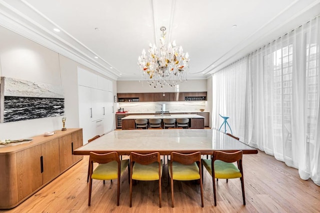 dining room featuring light hardwood / wood-style flooring, crown molding, a chandelier, and sink