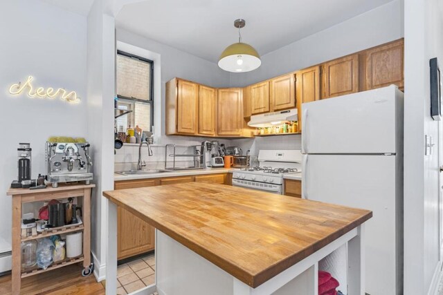 kitchen featuring decorative light fixtures, wooden counters, a sink, white appliances, and under cabinet range hood