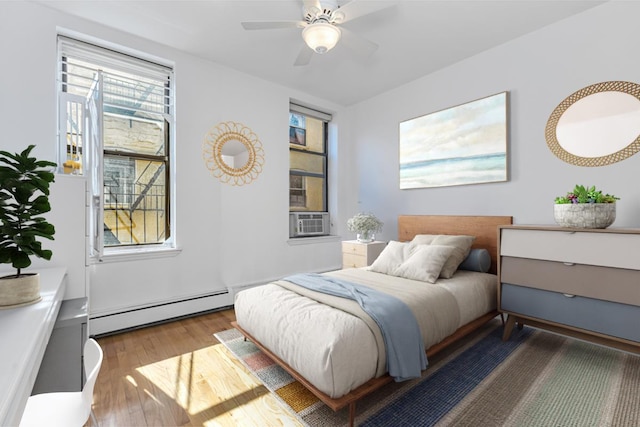 bedroom with ceiling fan, baseboard heating, cooling unit, and wood finished floors