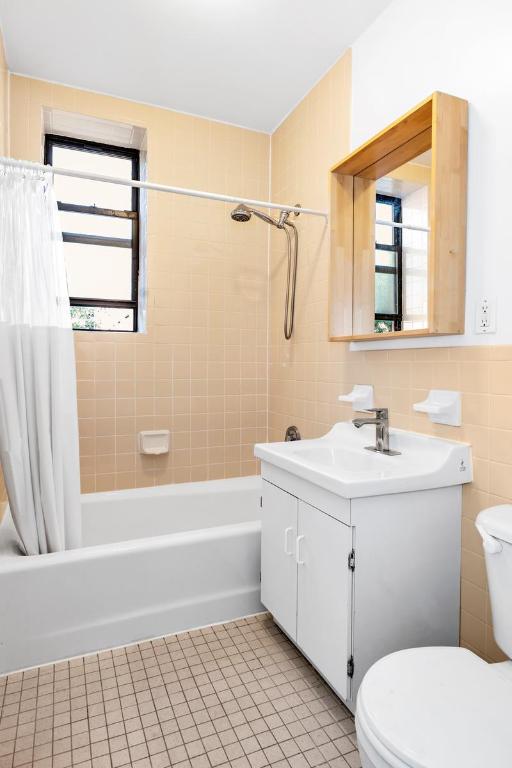 bathroom with toilet, shower / tub combo, vanity, tile walls, and tile patterned floors