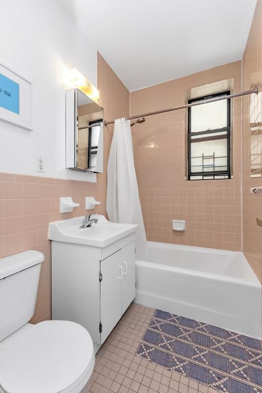 bathroom featuring tile walls, shower / bath combination with curtain, toilet, vanity, and tile patterned floors