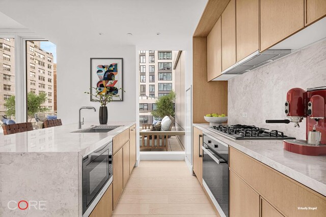 kitchen featuring stainless steel gas stovetop, oven, built in microwave, decorative backsplash, and sink