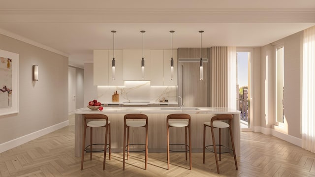 kitchen with light countertops, paneled built in refrigerator, a center island with sink, and backsplash