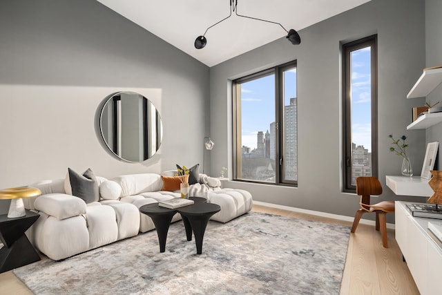 interior space featuring baseboards, a view of city, lofted ceiling, and wood finished floors