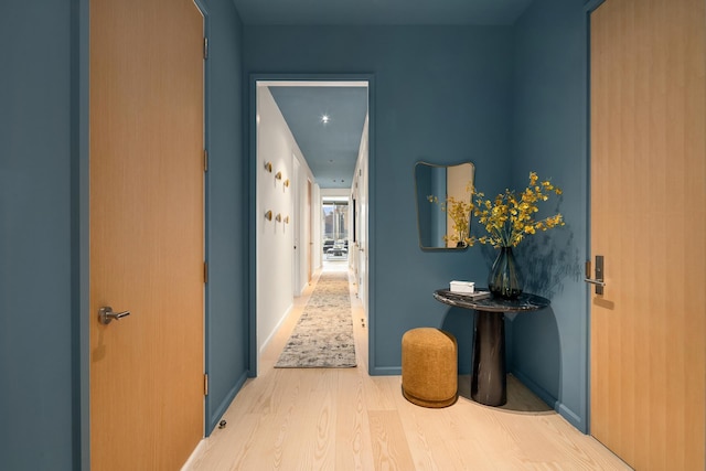 corridor with baseboards and wood finished floors