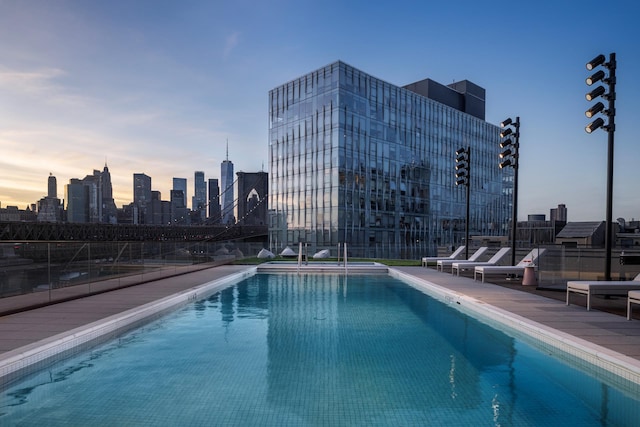 pool at dusk featuring a community pool and a city view