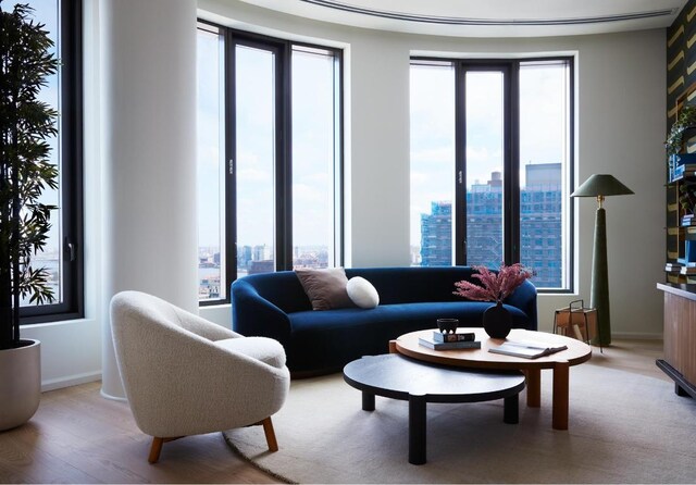 living area featuring a city view, plenty of natural light, light wood-type flooring, and baseboards