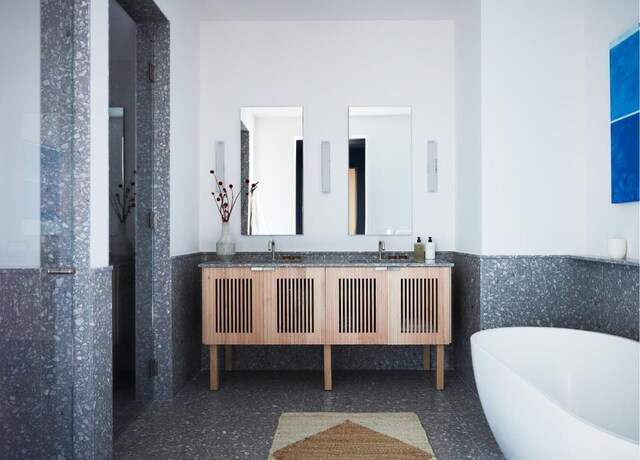 full bathroom with a sink, a freestanding tub, a wainscoted wall, and double vanity