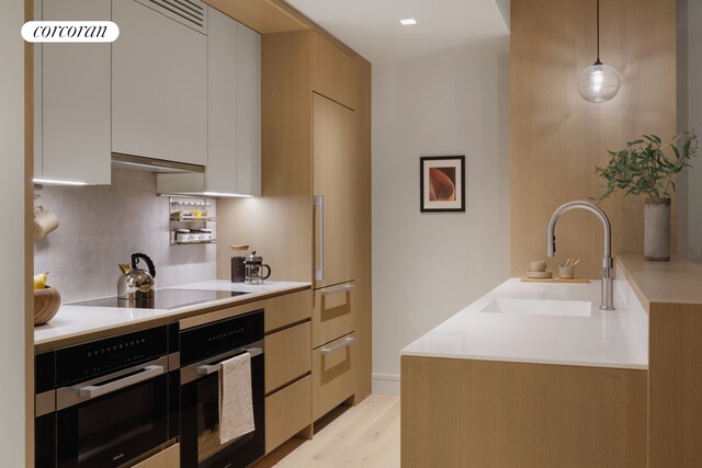 kitchen featuring sink, white cabinetry, wall oven, decorative light fixtures, and stainless steel oven