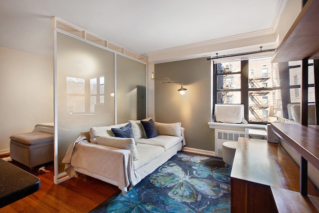 living area with baseboards, radiator heating unit, wood finished floors, and crown molding