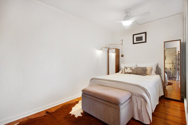 bedroom featuring a ceiling fan, baseboards, and wood finished floors