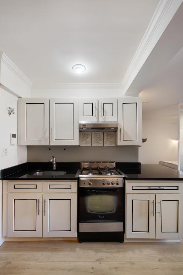 kitchen with under cabinet range hood, a sink, stainless steel range with gas cooktop, dark countertops, and crown molding