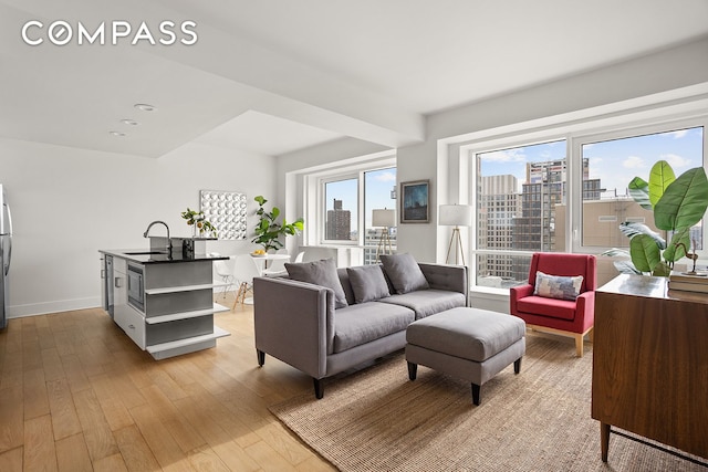 living room featuring a view of city, light wood-style flooring, and baseboards