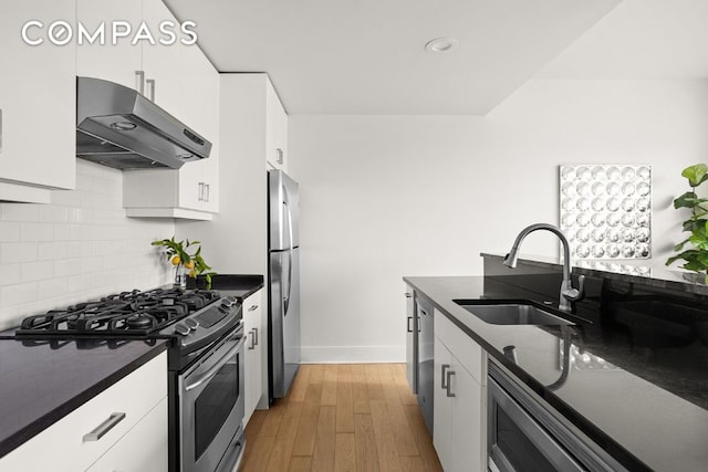 kitchen with sink, white cabinetry, light wood-type flooring, appliances with stainless steel finishes, and backsplash