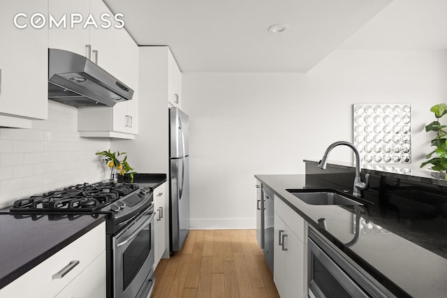 kitchen featuring decorative backsplash, a sink, dark countertops, stainless steel appliances, and under cabinet range hood