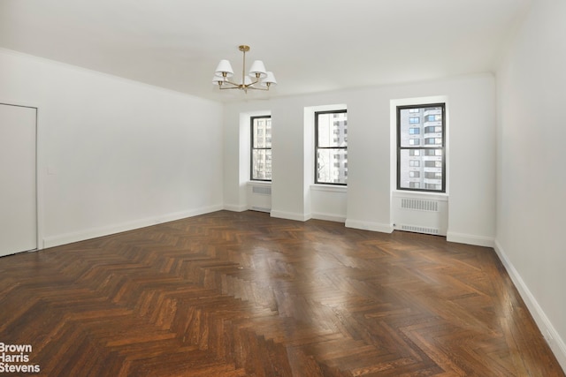 empty room featuring a notable chandelier, baseboards, a wealth of natural light, and radiator