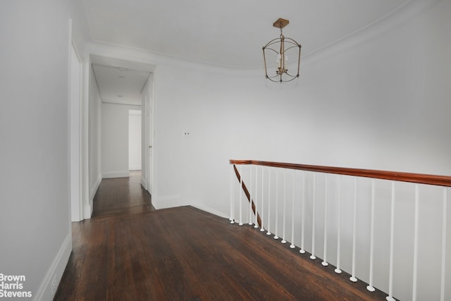 hall featuring a notable chandelier, wood finished floors, an upstairs landing, and baseboards