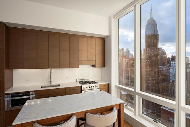 kitchen featuring oven, a wealth of natural light, sink, a breakfast bar area, and white gas range