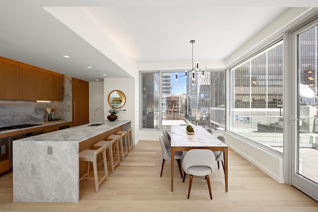 dining area with light wood-type flooring, a chandelier, baseboards, and recessed lighting