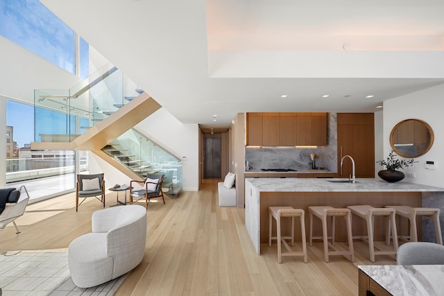 kitchen with a sink, decorative backsplash, a kitchen breakfast bar, light wood-style floors, and modern cabinets