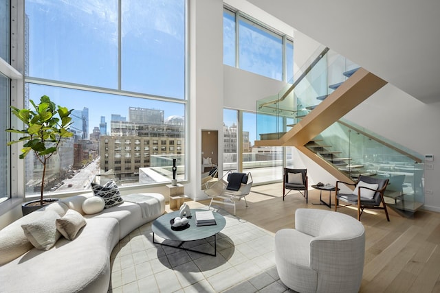 living room with a skyline view, stairway, wood finished floors, and a high ceiling