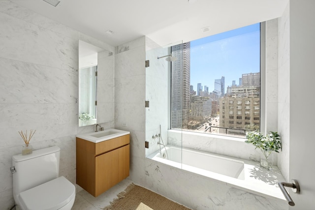 bathroom featuring tile walls, a view of skyline, a tub with marble appearance, toilet, and vanity