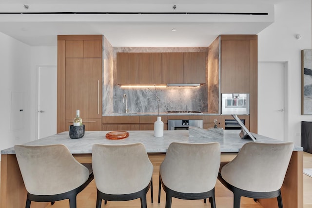kitchen featuring appliances with stainless steel finishes, a sink, brown cabinets, decorative backsplash, and modern cabinets