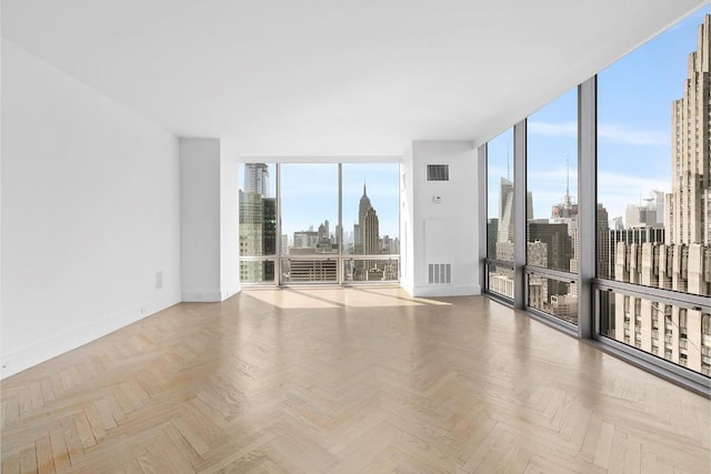 empty room with plenty of natural light, floor to ceiling windows, and light parquet flooring