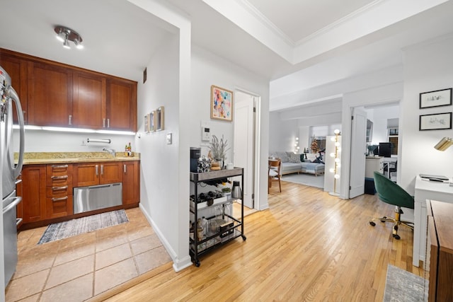 kitchen featuring sink, crown molding, light hardwood / wood-style floors, and stainless steel refrigerator