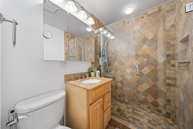 bathroom with a shower with shower door, vanity, and toilet