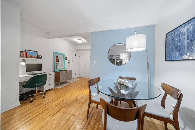 dining space with light hardwood / wood-style flooring and crown molding