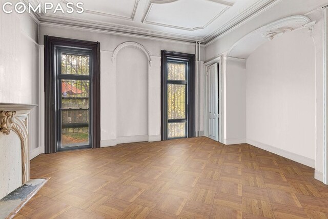 foyer entrance featuring a healthy amount of sunlight, light parquet floors, and ornamental molding