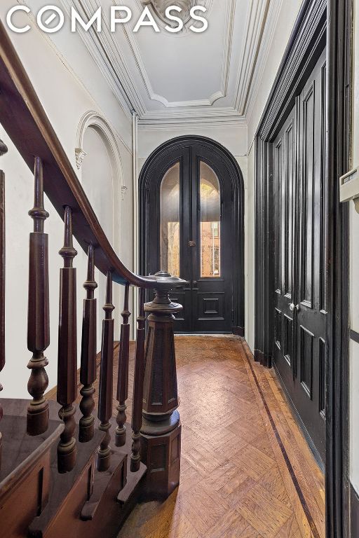 foyer featuring crown molding and dark parquet flooring