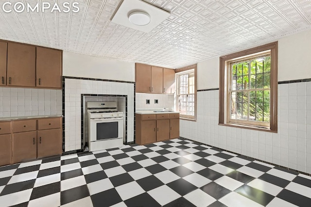 kitchen with tile walls and white range with gas cooktop