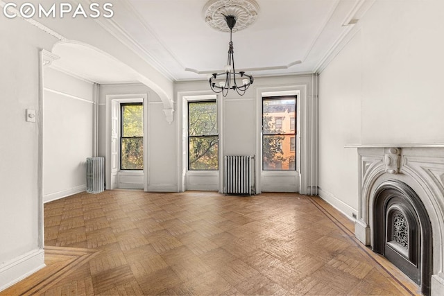 unfurnished dining area featuring an inviting chandelier, a tray ceiling, ornamental molding, parquet floors, and radiator heating unit